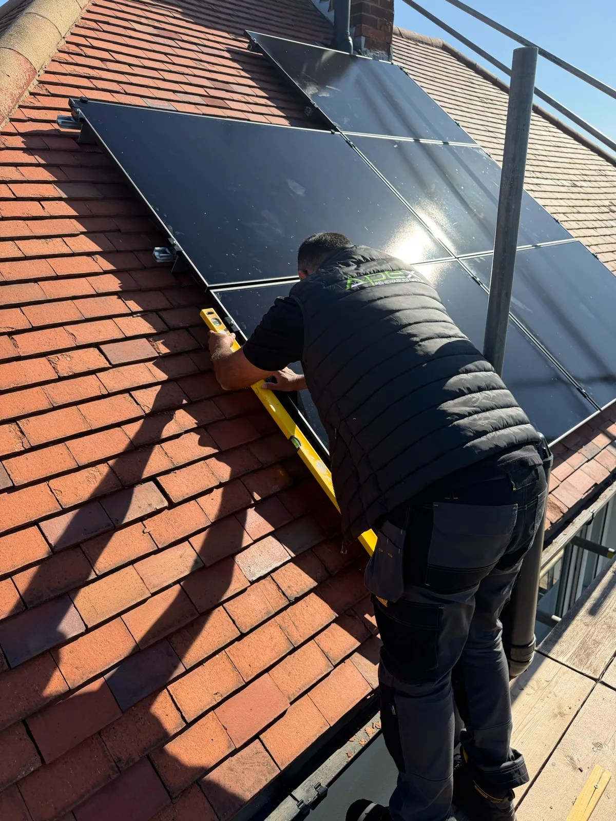 Apex installer levelling a solar panel by hand on a roof